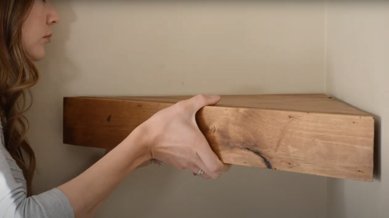 person mounting triangular corner shelf