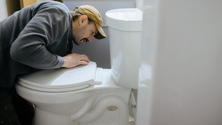 Man inspecting a broken toilet