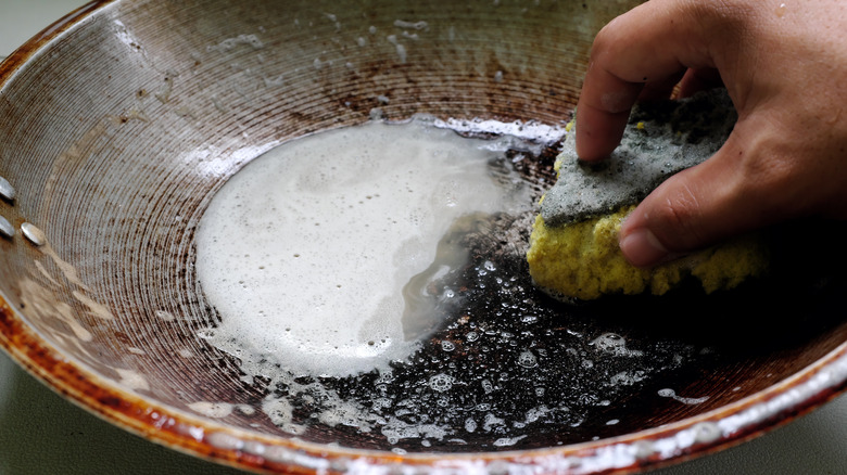 Person washing a scorched pot