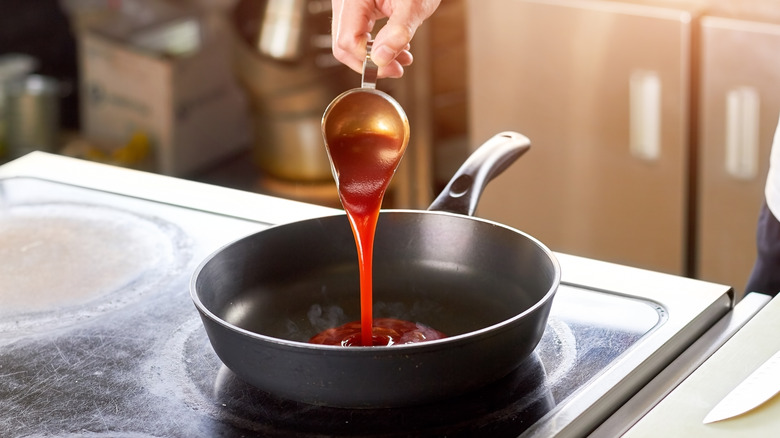 Person pouring tomato sauce into a pan