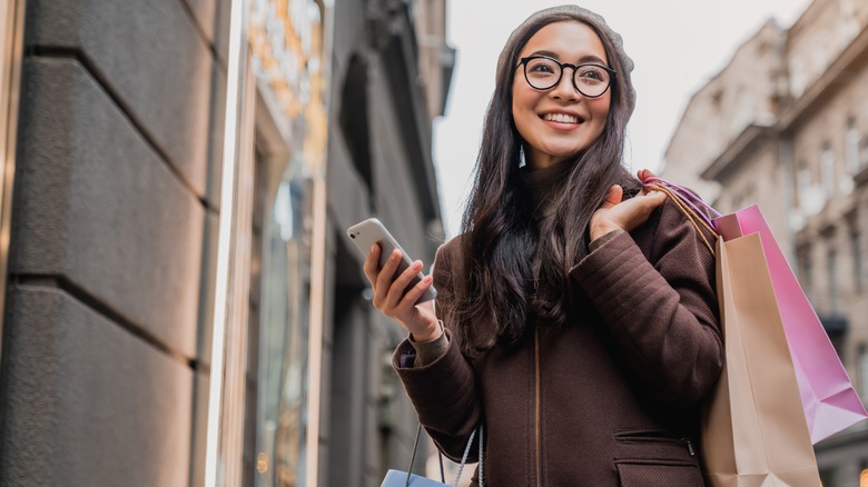 woman holding shopping bags and phone