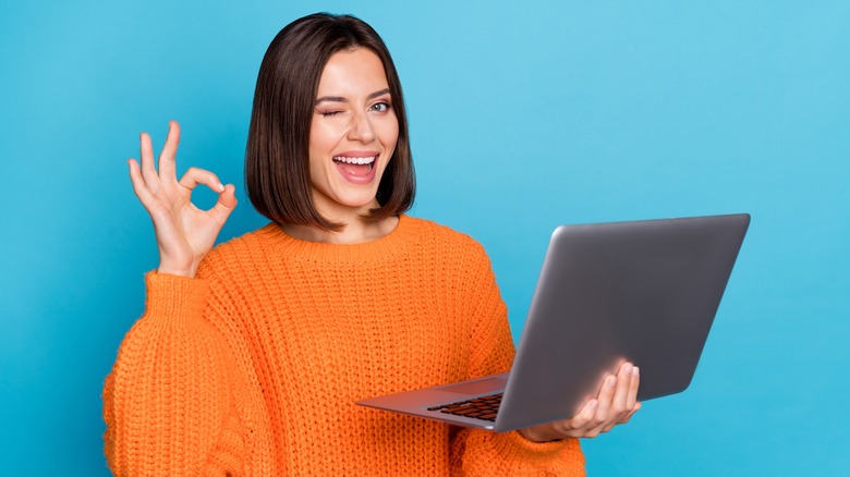 woman holding laptop and winking