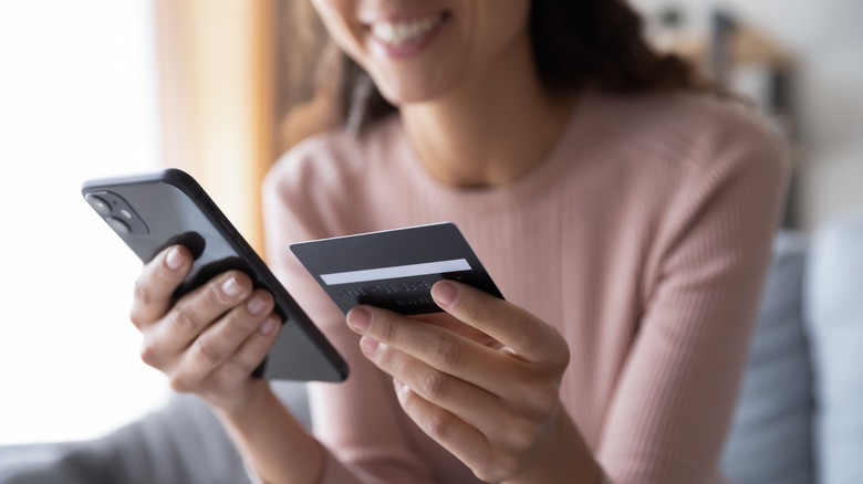 person holding credit card and phone