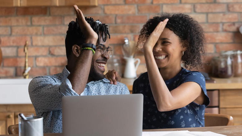 couple high-fiving at computer