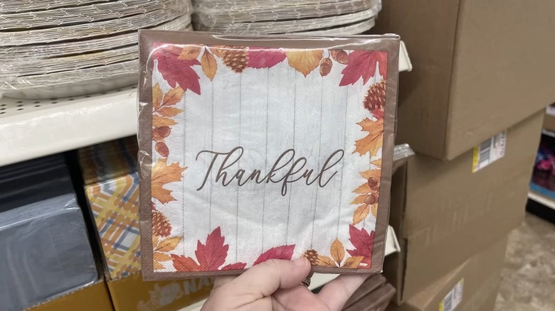 Holding fall-themed napkin with leaves in yellow and red