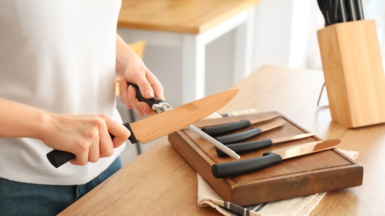 Woman sharpens knife on honing rod