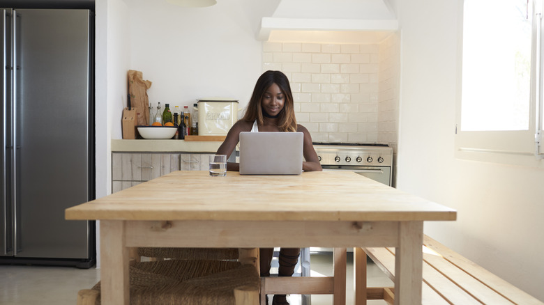 Woman using computer in kitchen