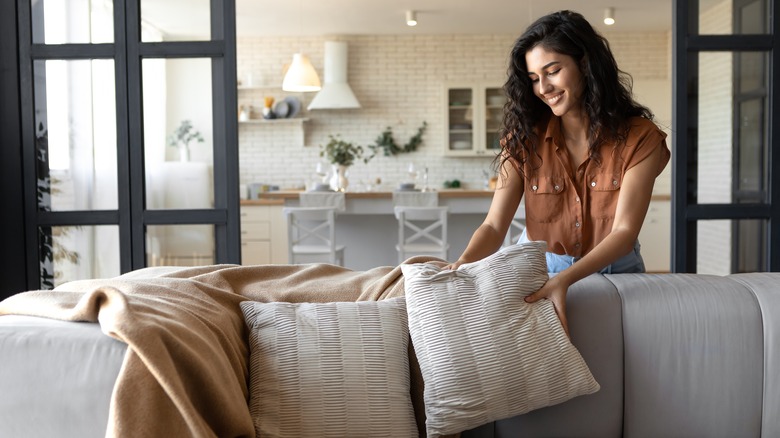 woman putting pillows on couch