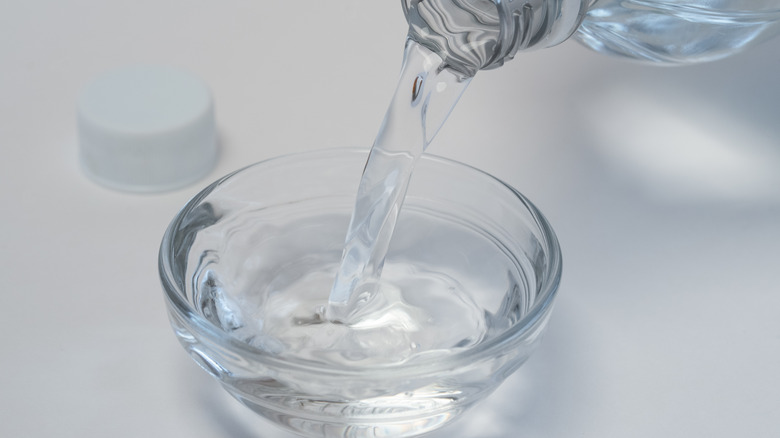 Pouring white distilled vinegar in bowl