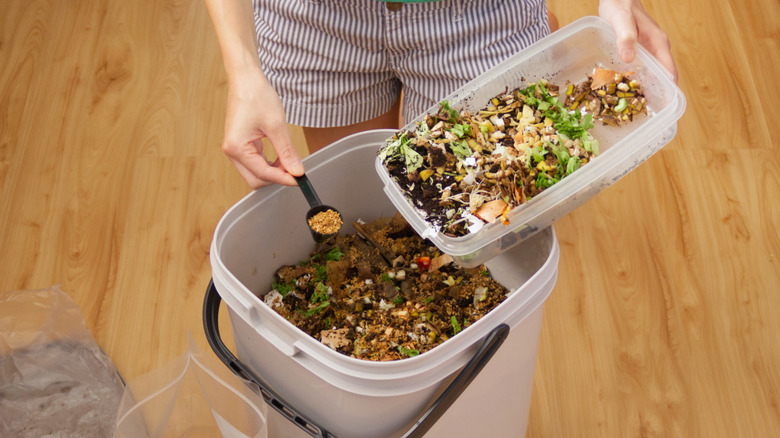 A person sprinkles Bokashi bran into a compost bin