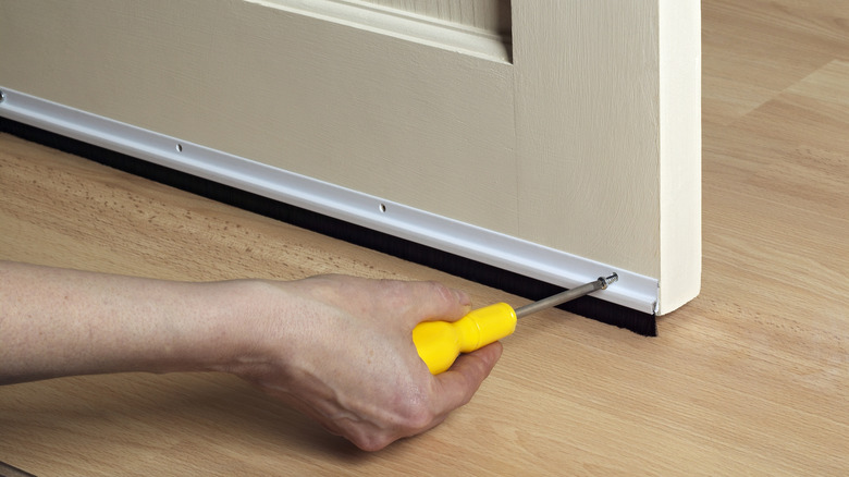 A person installing a door sweep