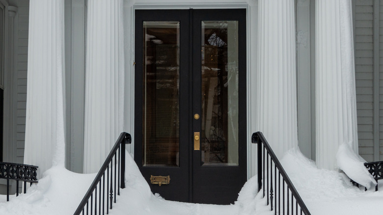 Black double front doors on a snowy day