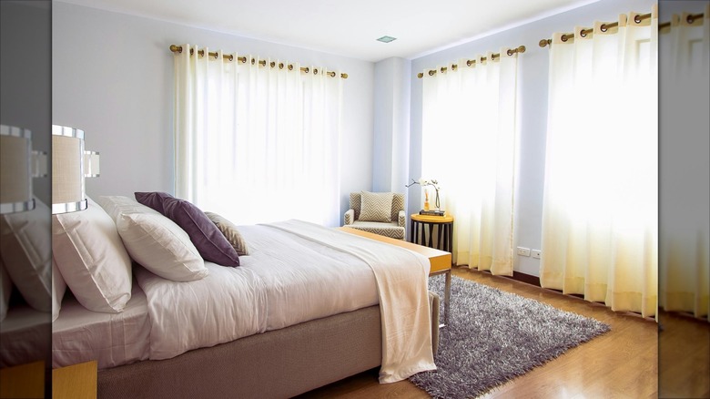 Sheer curtains hang at a hover length in a neutral bedroom