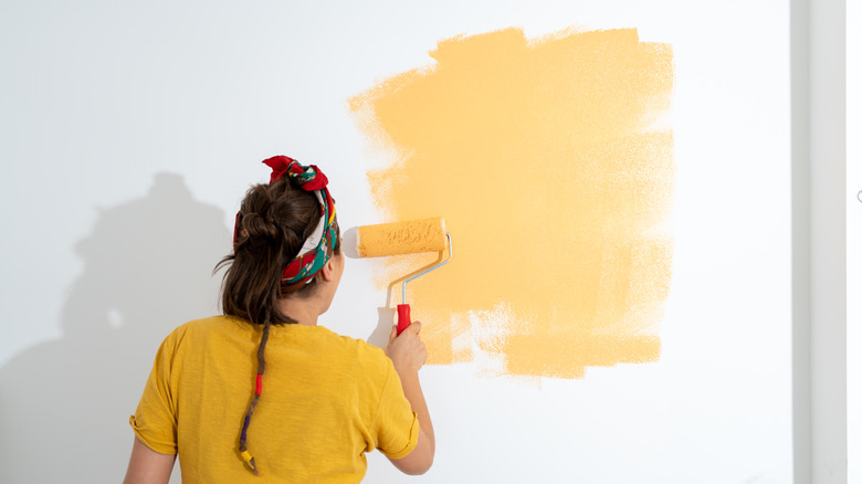 Woman painting walls yellow