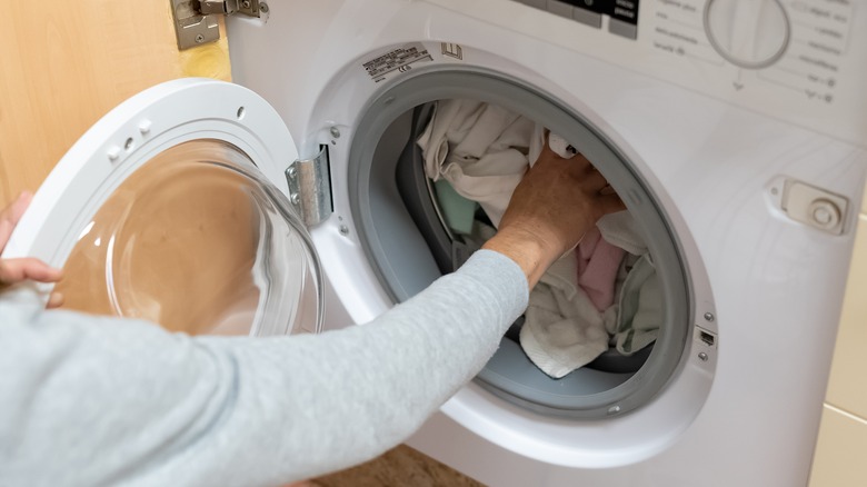 person reaching into full washer