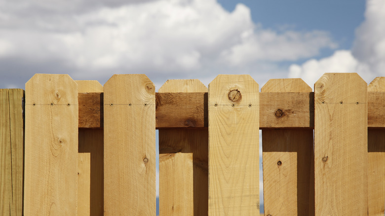 A cedar fence against a cloudy blue sky