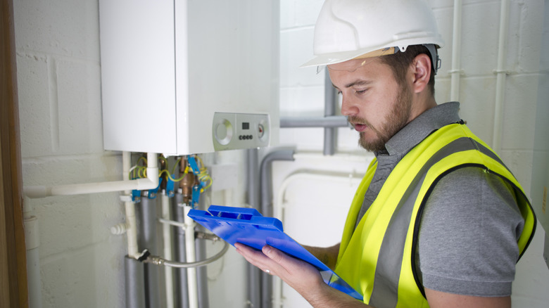 A plumber checking documentation on a tankless water heater