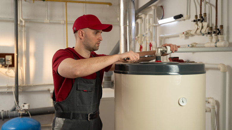 A man adjustuing the hose on a tank-based water heater