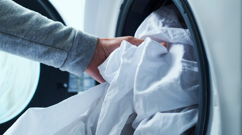 Hand adding sheet to washer