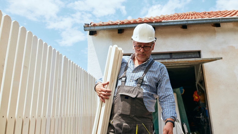 Professional fence repair worker carrying fence materials