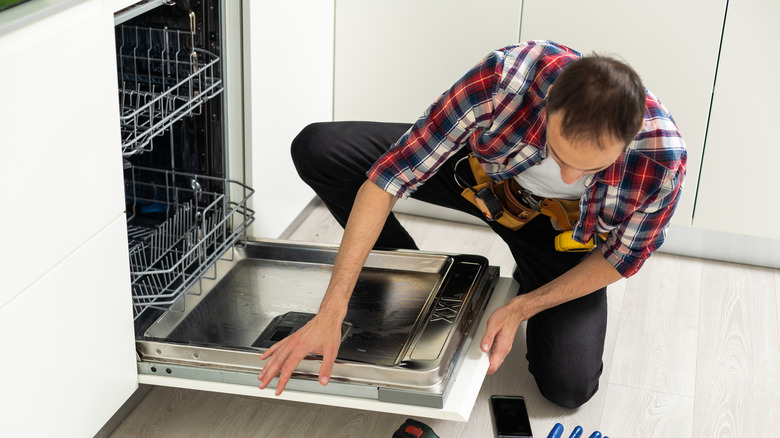 Man installing dishwasher in kitchen