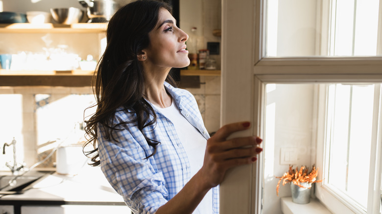 woman looking out uncovered windows