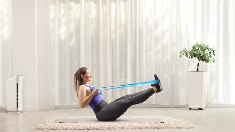 woman exercising in front of white sheer curtains