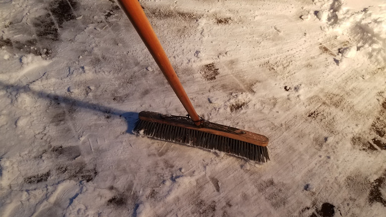 Sweeping snow off deck with broom