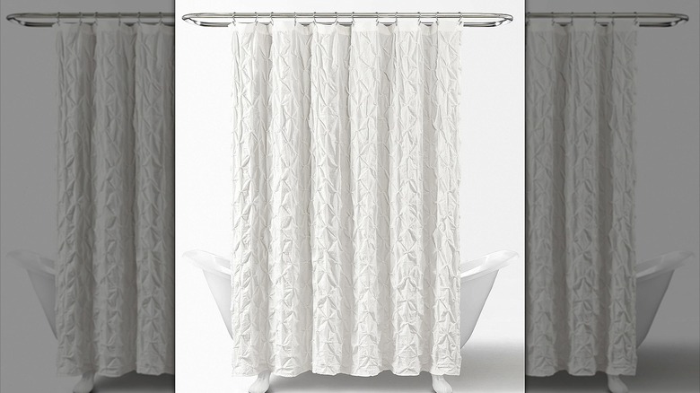 White pintuck shower curtain hanging in front of a tub