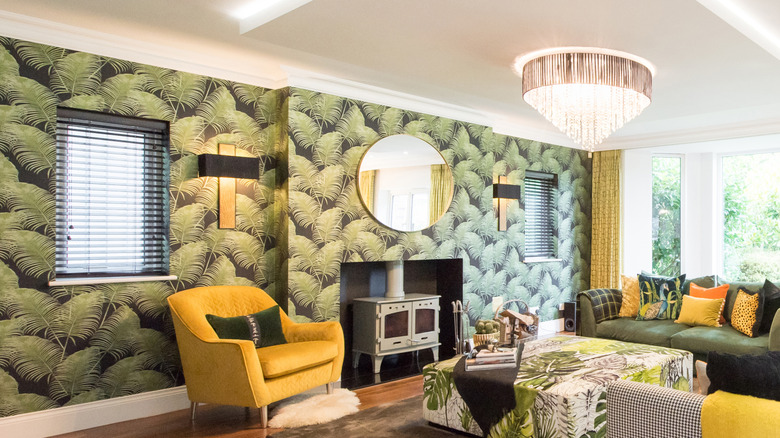 Living room with leafy wallpaper, yellow and green seats with throw pillows, a lighting fixture