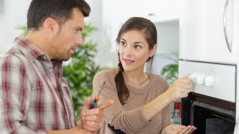 Woman and repairman discussing oven