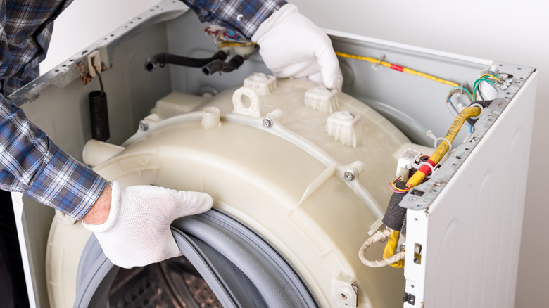 A person installing a new washing machine drum