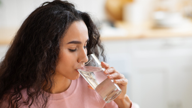 woman drinking glass of water kitchen