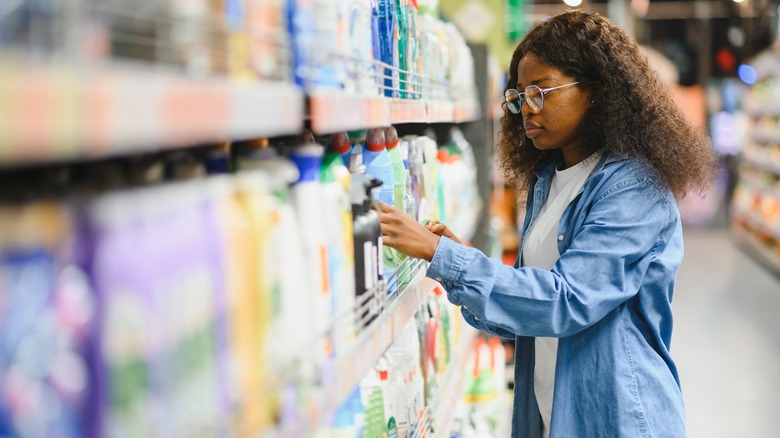 A woman shops for laundry detergent in a grocery store cleaning aisle