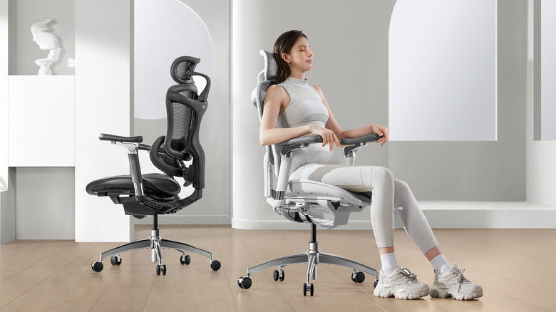 Woman sits in white Sihoo C300 Pro office chair. An empty black chair is beside her.