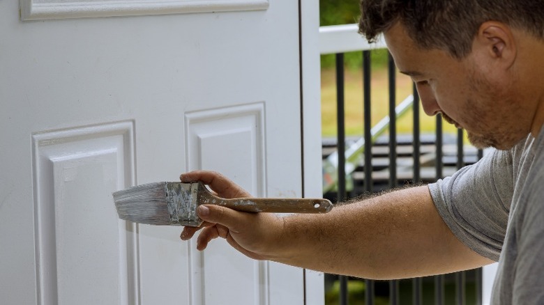 Man painting white door