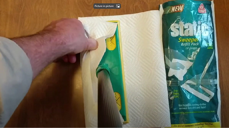 Hand wrapping a paper towel around a swiffer