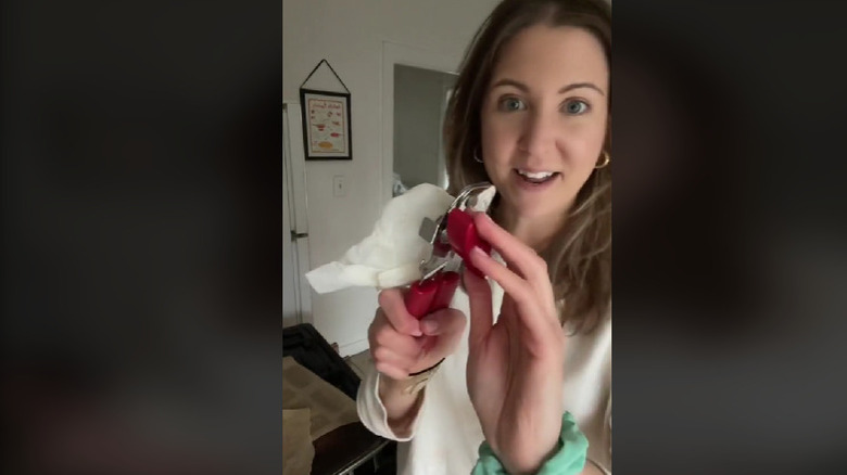 A woman cleaning a can opener with a paper towel