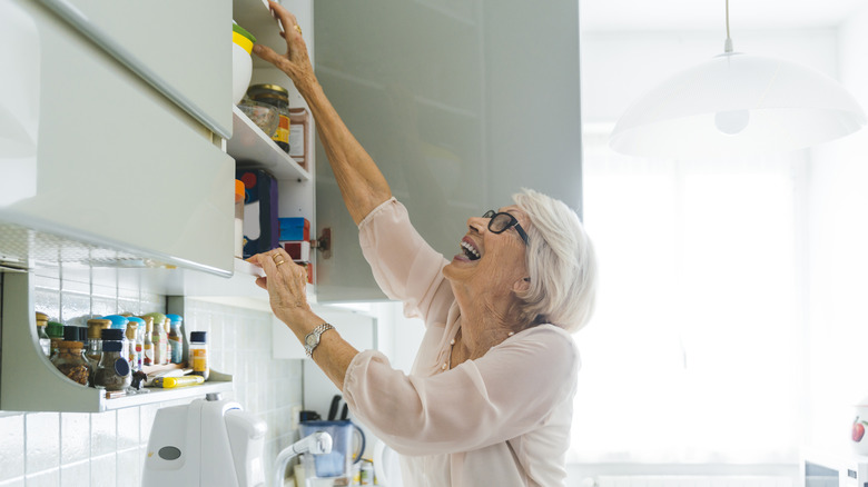 Woman reaching up in cabinet