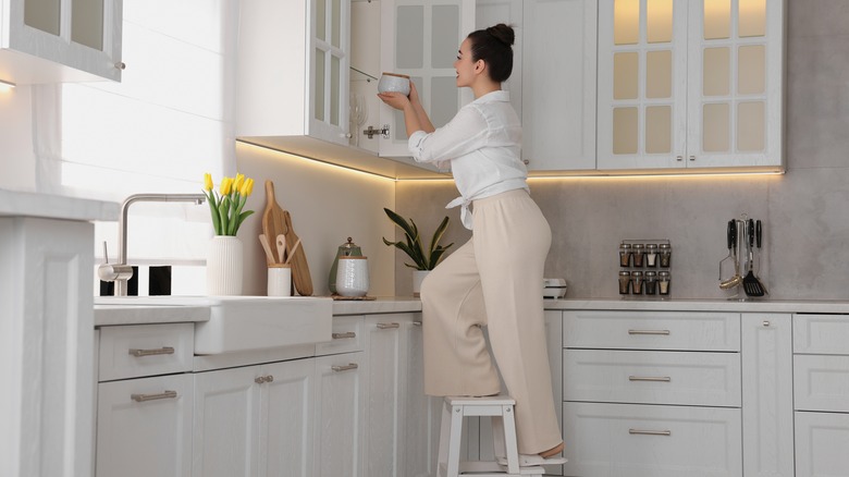 Woman climbing on step ladder