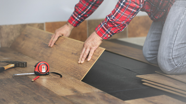 Person installing wooden plank flooring