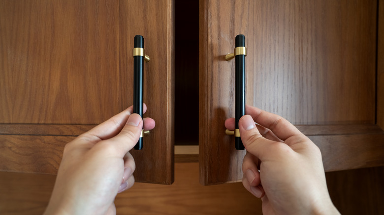 Hands opening kitchen cabinet doors