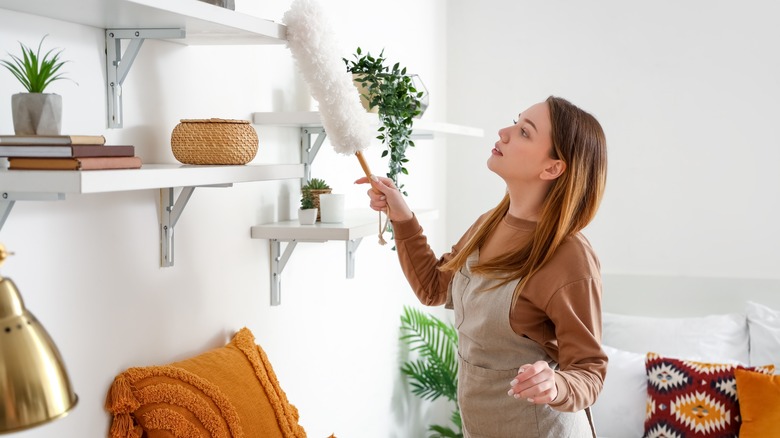 Person dusting shelf