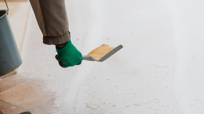 Hand scooping sand over snow