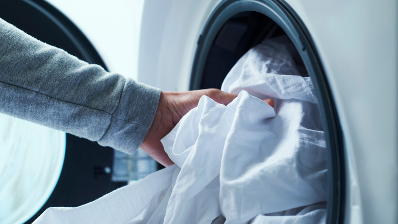 hand putting sheet into washer