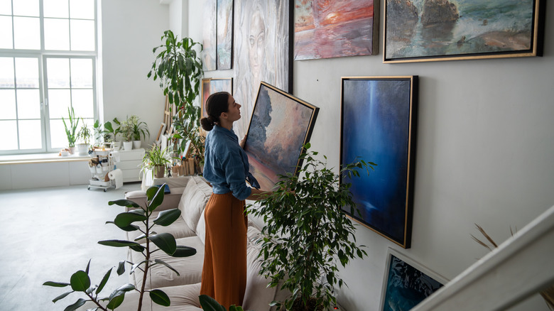 A person hanging artwork on a gallery accent wall