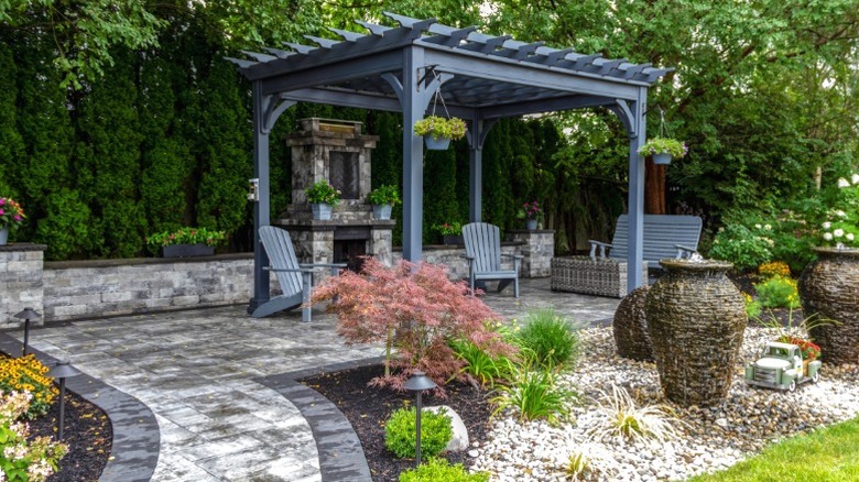 A patio area with fireplace, seating, and black pergola