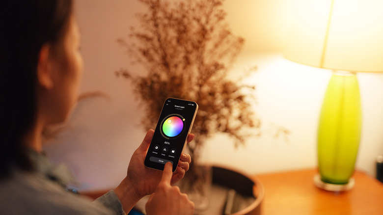 Woman controlling smart light bulb using an app on her phone