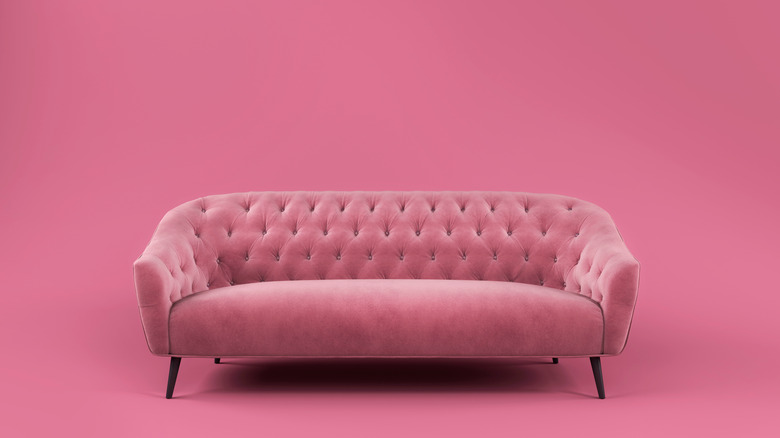 A pink velvet sofa against a pink wall