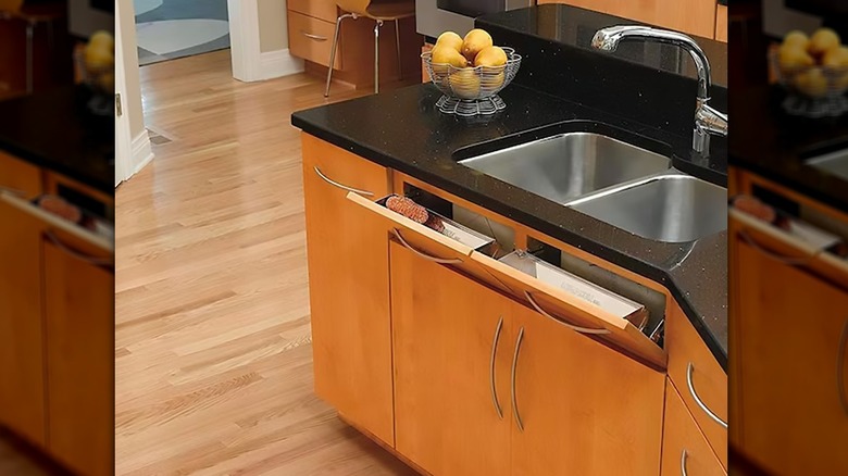 Tip-out tray installed in front of a kitchen sink